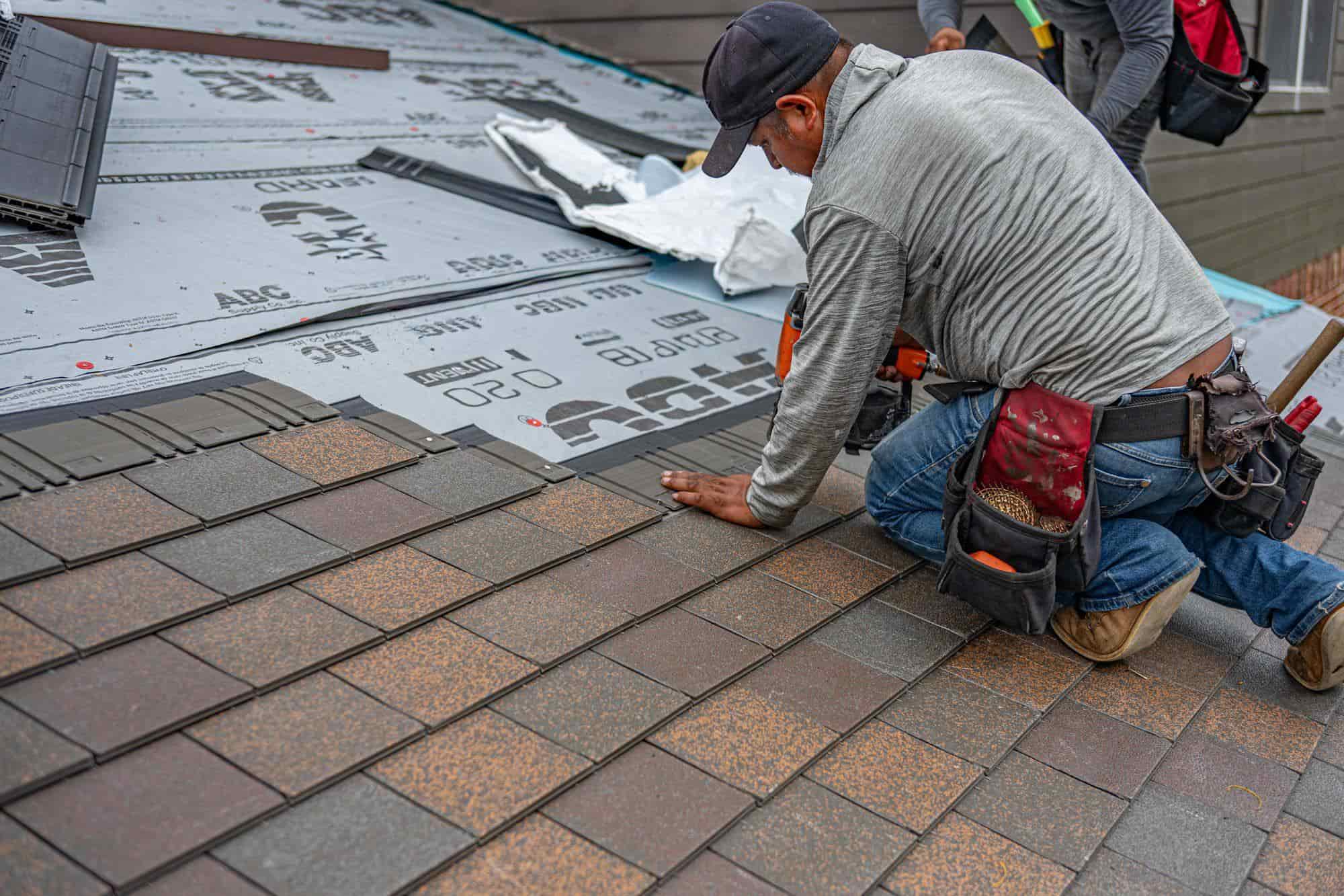 A roofer installing shingles on a home